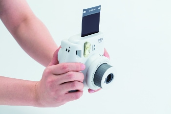 Instax Mini 9 in white in a photographers hand